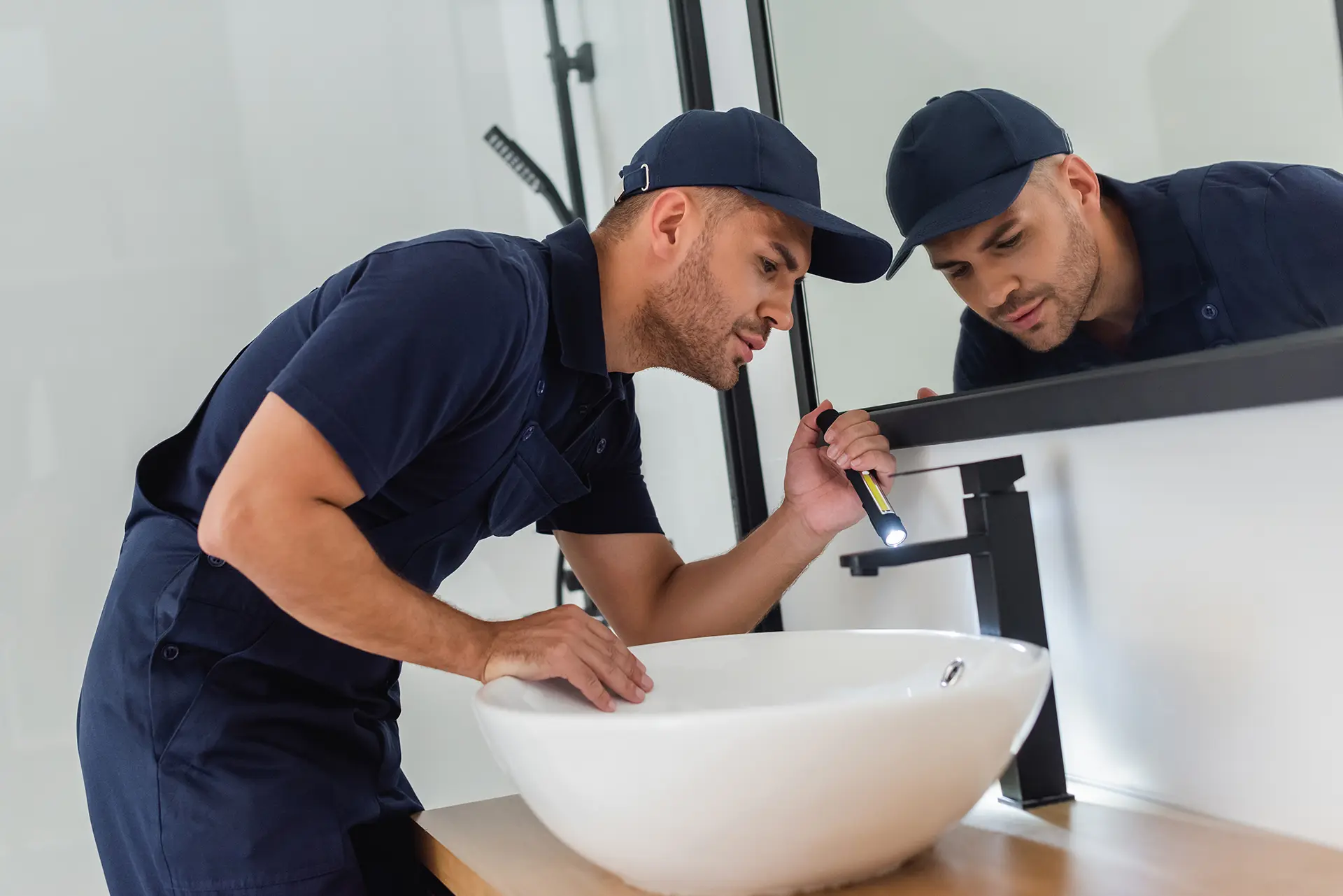 Plumber inspecting the sink plumbing in a modern bathroom
